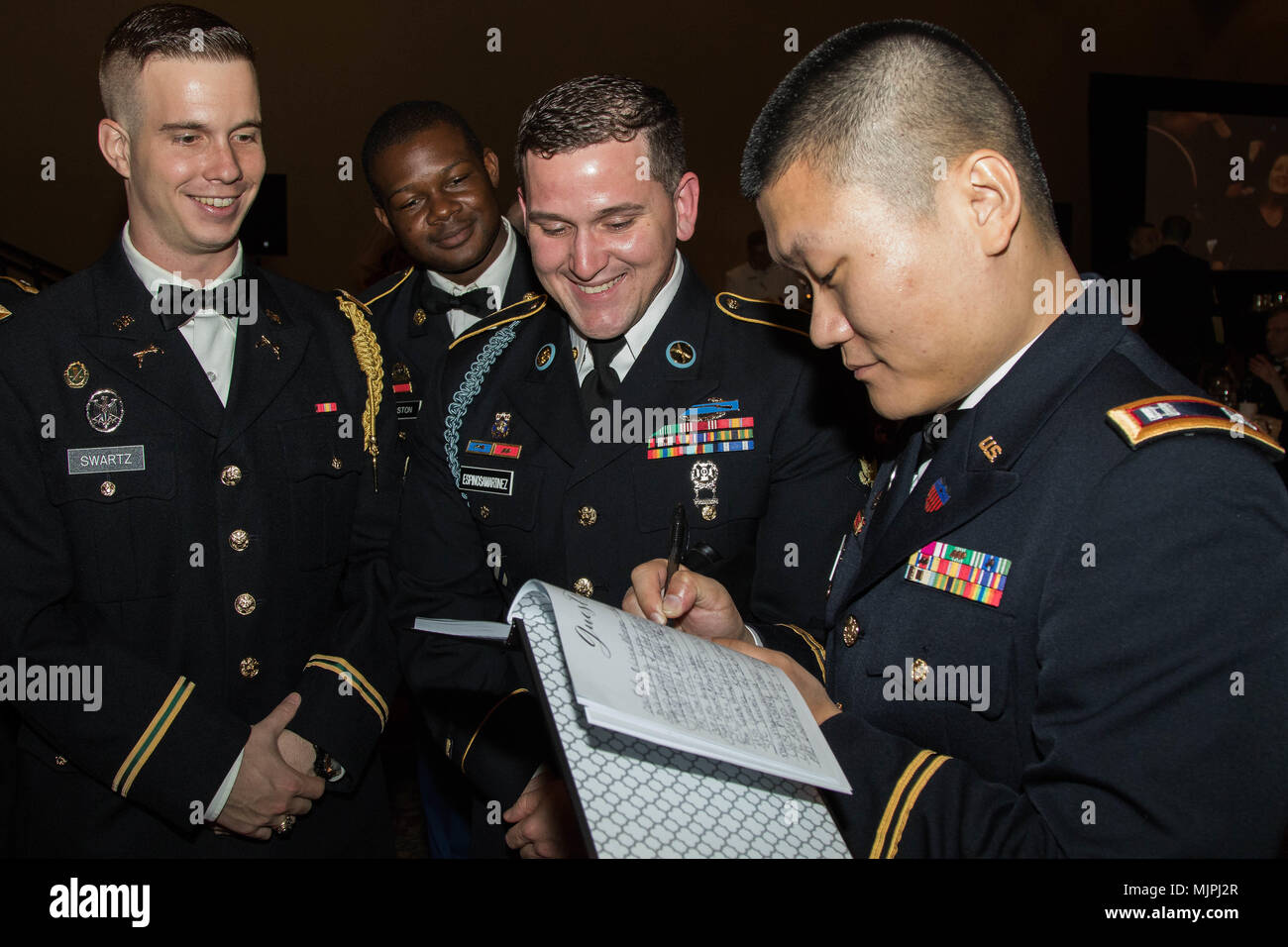 Dressed in their Army Service Uniforms, Soldiers from the 143d Sustainment Command (Expeditionary) sign a the black book during the during the Maj. Gen. Francisco A. Espaillat Victory Ball conducted at the Rosen Shingle Creek resort in Orlando, Fla., Dec. 16, 2017. The Victory Ball presented a unique opportunity for Soldiers assigned throughout the Command’s vast area of operations don their suits, gowns or dress uniforms and surround themselves with new and familiar faces in a fun and friendly atmosphere. (U.S. Army photo by Sgt. John L. Carkeet IV, 143d ESC) Stock Photo