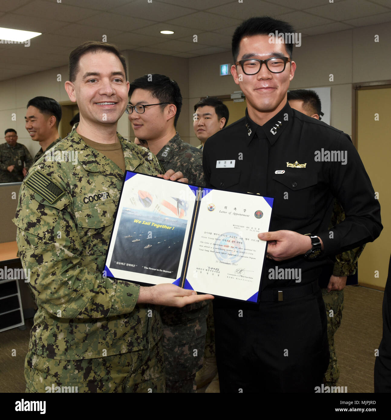 171221-N-TB148-047 BUSAN, Republic of Korea (Dec. 21, 2017) Rear Adm. Brad Cooper, commander, U.S. Naval Forces Korea (CNFK), presents Lt. Yu, Jin Hong with a letter of appointment for his selection to the 'Great Young Minds' Junior Officers' Engagement and Cooperation Program. The 'Great Young Minds' initiative brings together hand-selected, young officers from the ROK and U.S. navies and challenges them to develop innovative solutions to further enhance the ROK -U.S. alliance of the future. (U.S. Navy photo by Mass Communication Specialist Seaman William Carlisle) Stock Photo