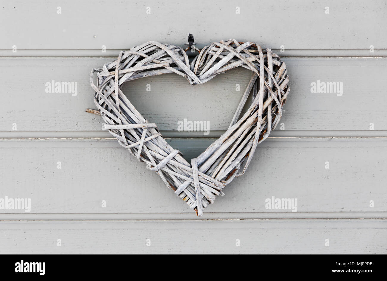 Closeup of a grey heart shaped ornament on a grey wooden door. Stock Photo