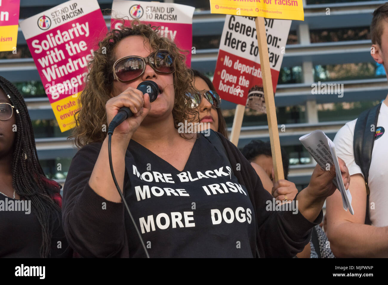 London, UK. 5th May 2018. A woman wearing a 'More Blacks More Irish More Dogs' t-shirt speaks at the protest outside the Home Office calling for Theresa May's racist 2014 Immigration Act to be repealed and an immediate end to the deportation and detention of Commonwealth citizens, with those already deported to be bought back to the UK. There should be an end to the 'h Credit: Peter Marshall/Alamy Live News Stock Photo