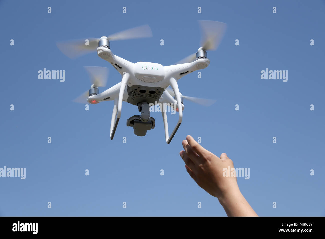 Hand catching drone aircraft in blue sky background, camera operator concept of aerial photography Stock Photo