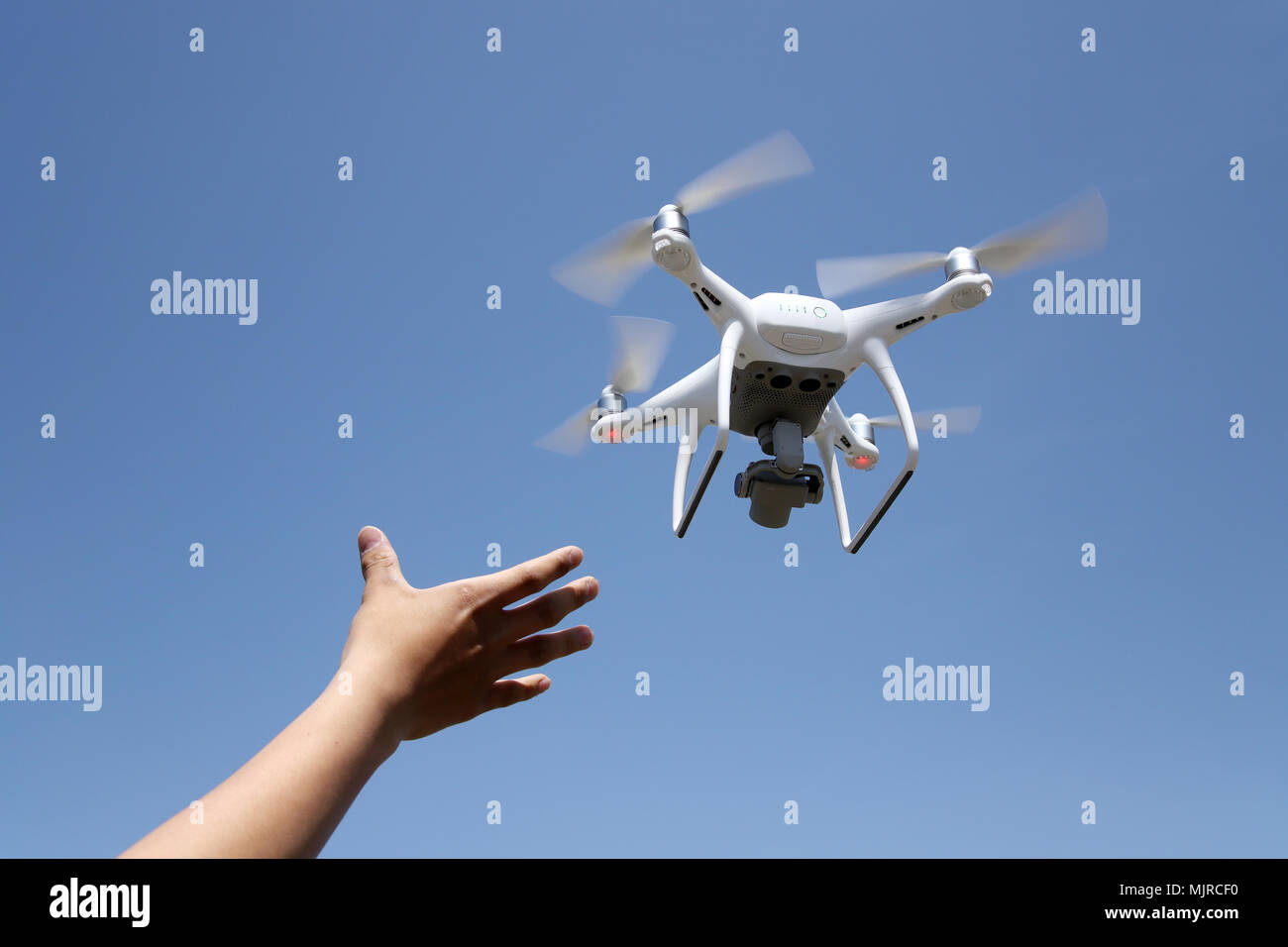Hand catching drone aircraft in blue sky background, camera operator