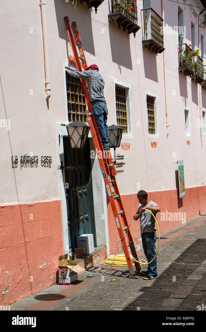 QUITO, ECUADOR - OCTOBER 27, 2015: workers with a ladder fix a window in Calle La Ronda, typical and colorful colonial street in historic district Stock Photo
