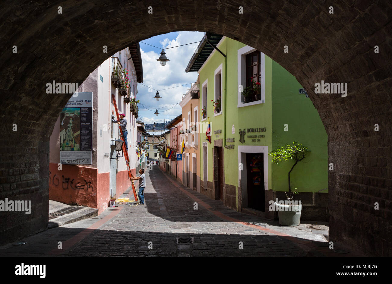 QUITO, ECUADOR - OCTOBER 27, 2015: workers fix a window in Calle La Ronda, typical and colorful colonial street in historic district, viewed through t Stock Photo