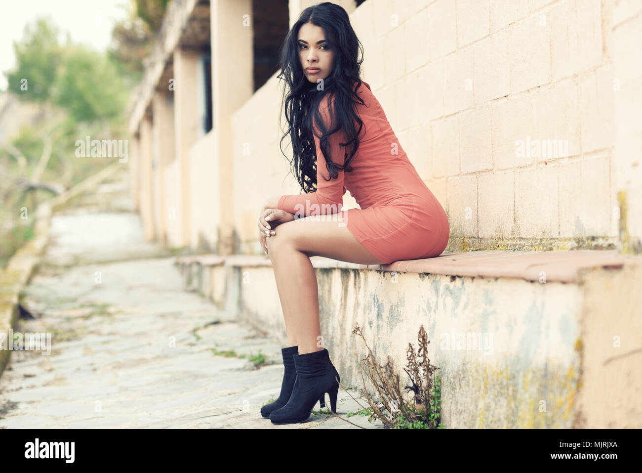 Portrait of hispanic young woman wearing casual orange dress in urban background Stock Photo