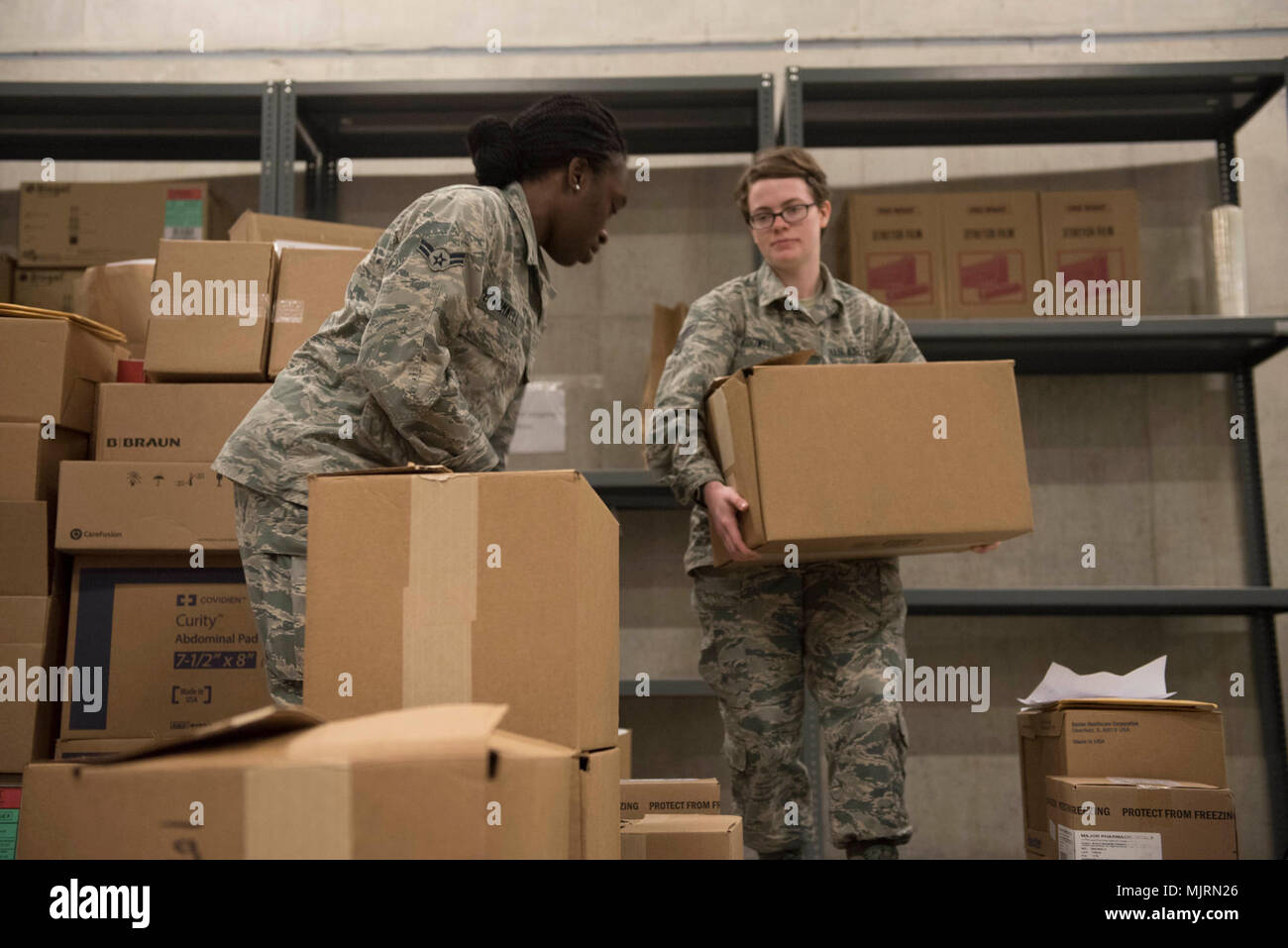 U.S. Air Force Airman 1st Class’ Ashley Cromwell, left, and Gabrielle McDowell, right, both 18th Medical Group medical material technicians, stack boxes of medical supplies for palletizing March 21, 2018, at Kadena Air Base, Japan. Many items, such as first-aid kits and medications, must be checked for quality before they can leave the warehouse. Armed Forces and civilians displaying courage bravery dedication commitment and sacrifice Stock Photo