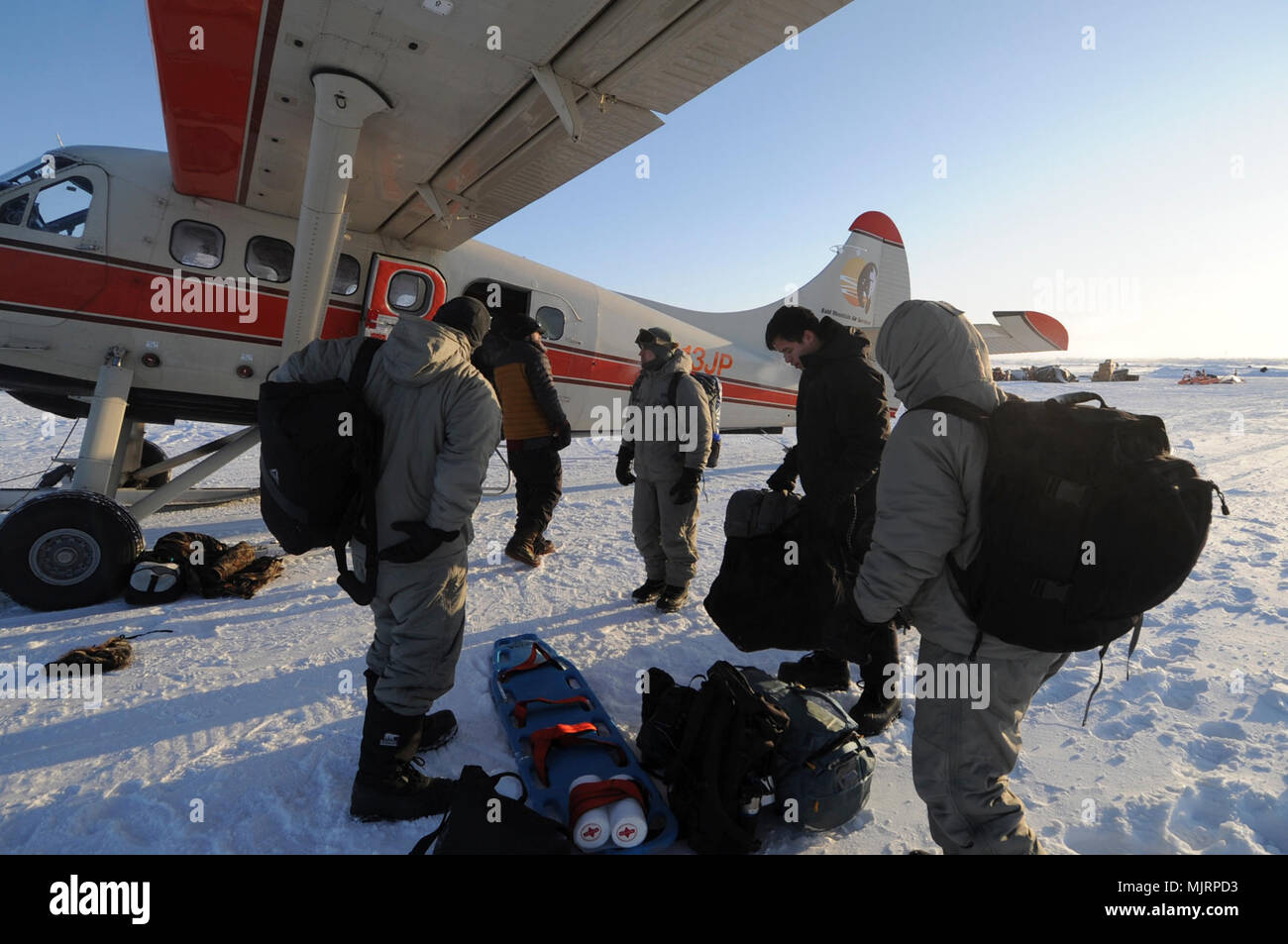 BEAUFORT SEA (March 21, 2018) Personnel at Ice Camp Skate load equipment and bags onboard an aircraft prior to departing camp during Ice Exercise (ICEX) 2018. ICEX 2018 is a five-week exercise that allows the Navy to assess its operational readiness in the Arctic, increase experience in the region, advance understanding of the Arctic environment, and continue to develop relationships with other services, allies and partner organizations. Armed Forces and civilians displaying courage bravery dedication commitment and sacrifice Stock Photo