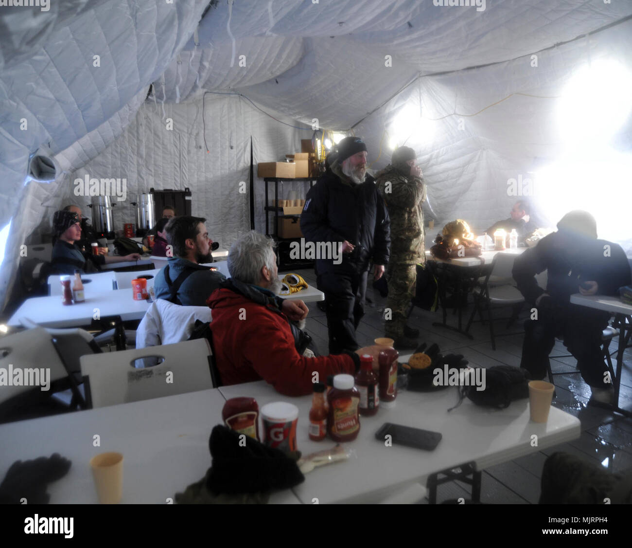 BEAUFORT SEA (March 21, 2018) Personnel at Ice Camp Skate get warm and grab a bite to eat in the mess tent during Ice Exercise (ICEX) 2018. ICEX 2018 is a five-week exercise that allows the Navy to assess its operational readiness in the Arctic, increase experience in the region, advance understanding of the Arctic environment, and continue to develop relationships with other services, allies and partner organizations. Armed Forces and civilians displaying courage bravery dedication commitment and sacrifice Stock Photo