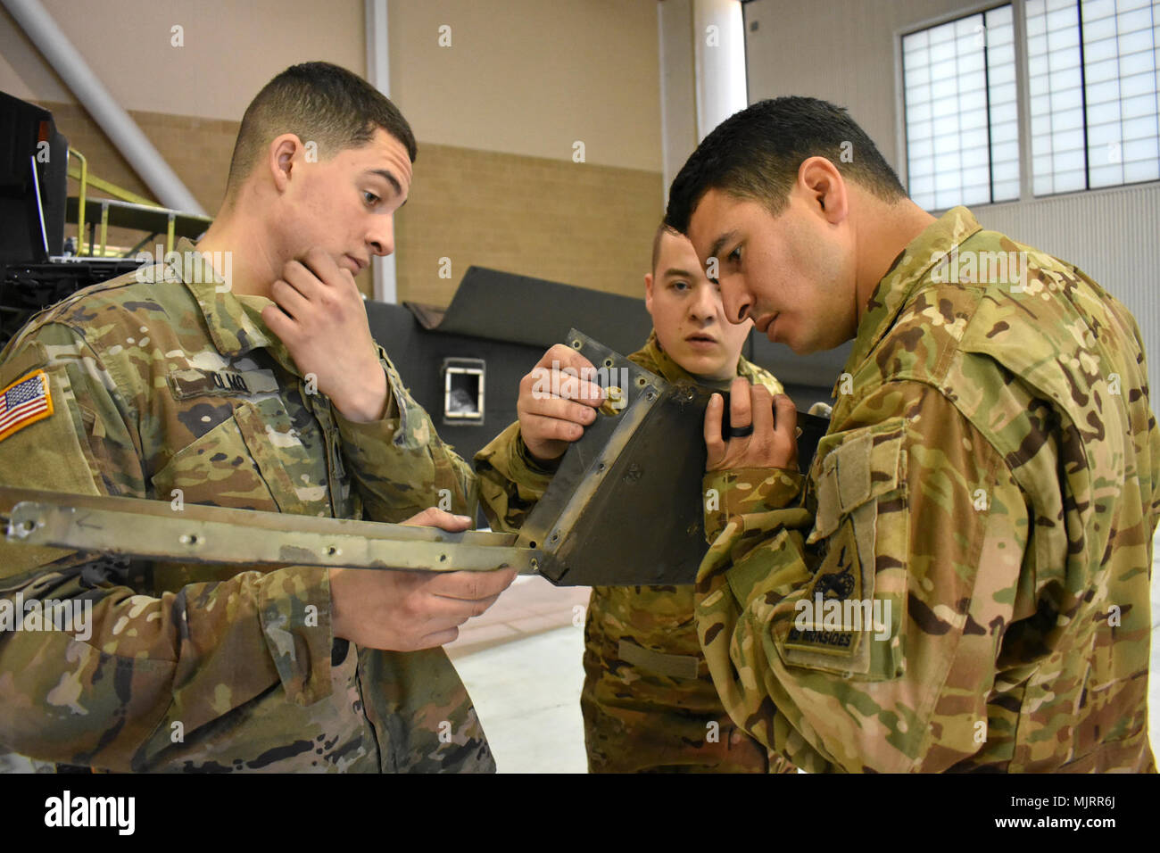 From left, Spc. Nicholas Olmo, Spc. Brandon Arthur and Staff Sgt. Javier Fuentes, all assigned to 1st Battalion, 501st Aviation Regiment, Combat Aviation Brigade, 1st Armored Division, inspect an upper support fairing from an AH-64D Apache helicopter in the battalion’s hanger at Fort Bliss March 1, 2018, while conducting in-depth maintenance on the aircraft. Armed Forces and civilians displaying courage bravery dedication commitment and sacrifice Stock Photo