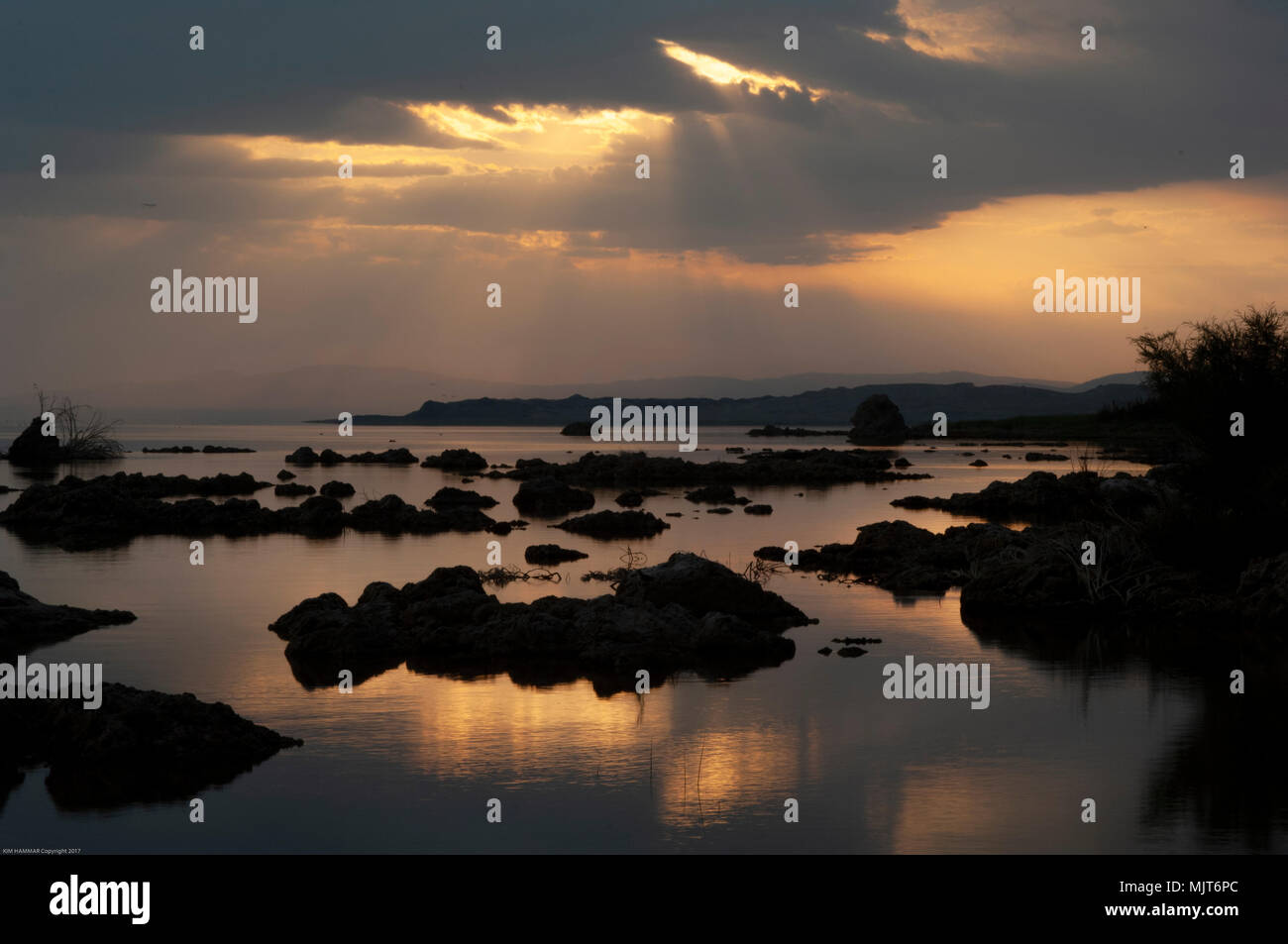 Sunrays break through the clouds over tufa silhouettes at Mono Lake during sunrise. Stock Photo