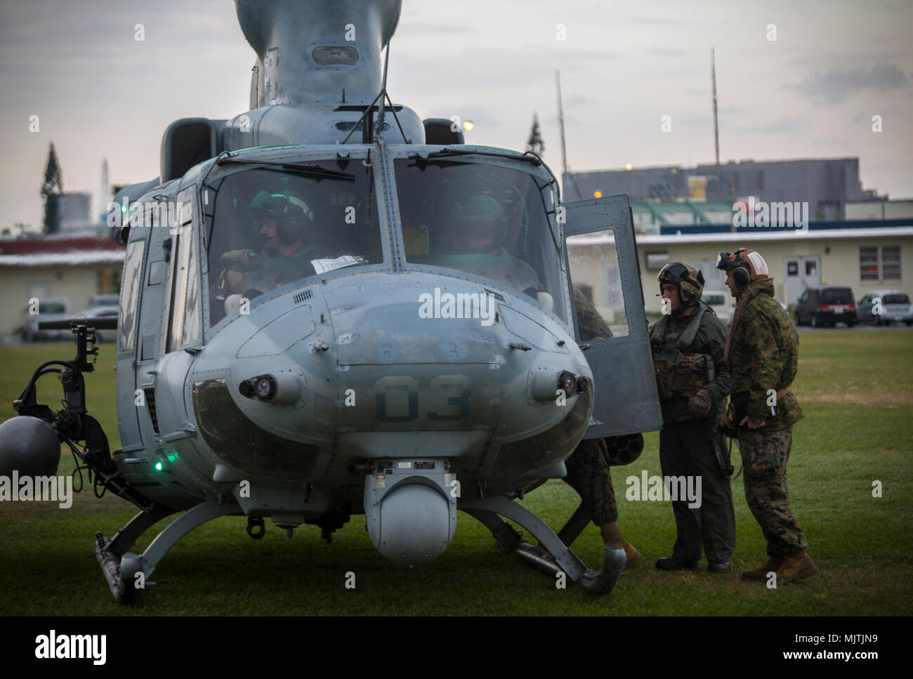 A crew chief boards passengers on a UH-1Y Venom at Camp Foster, Okinawa, Japan, December 15, 2017. Marine Light Attack Helicopter Squadron 369 provided Lt. Gen. Brian D. Beaudreault, deputy commandant of plans, policies and operations, a flight around the Okinawa Prefecture to assess the service quality of the Marine Corps chowhalls. The “gunfighters’” readiness to act upon a moment’s notice is crucial to maintaining a stronger, more capable forward deployed force in the Indo-Asia-Pacific region. HMLA-369, Marine Aircraft Group 39, 3rd Marine Aircraft Wing, is currently forward deployed under Stock Photo