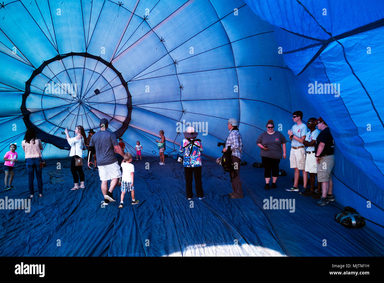 People exploring the inside of a partially inflated hot air balloon at