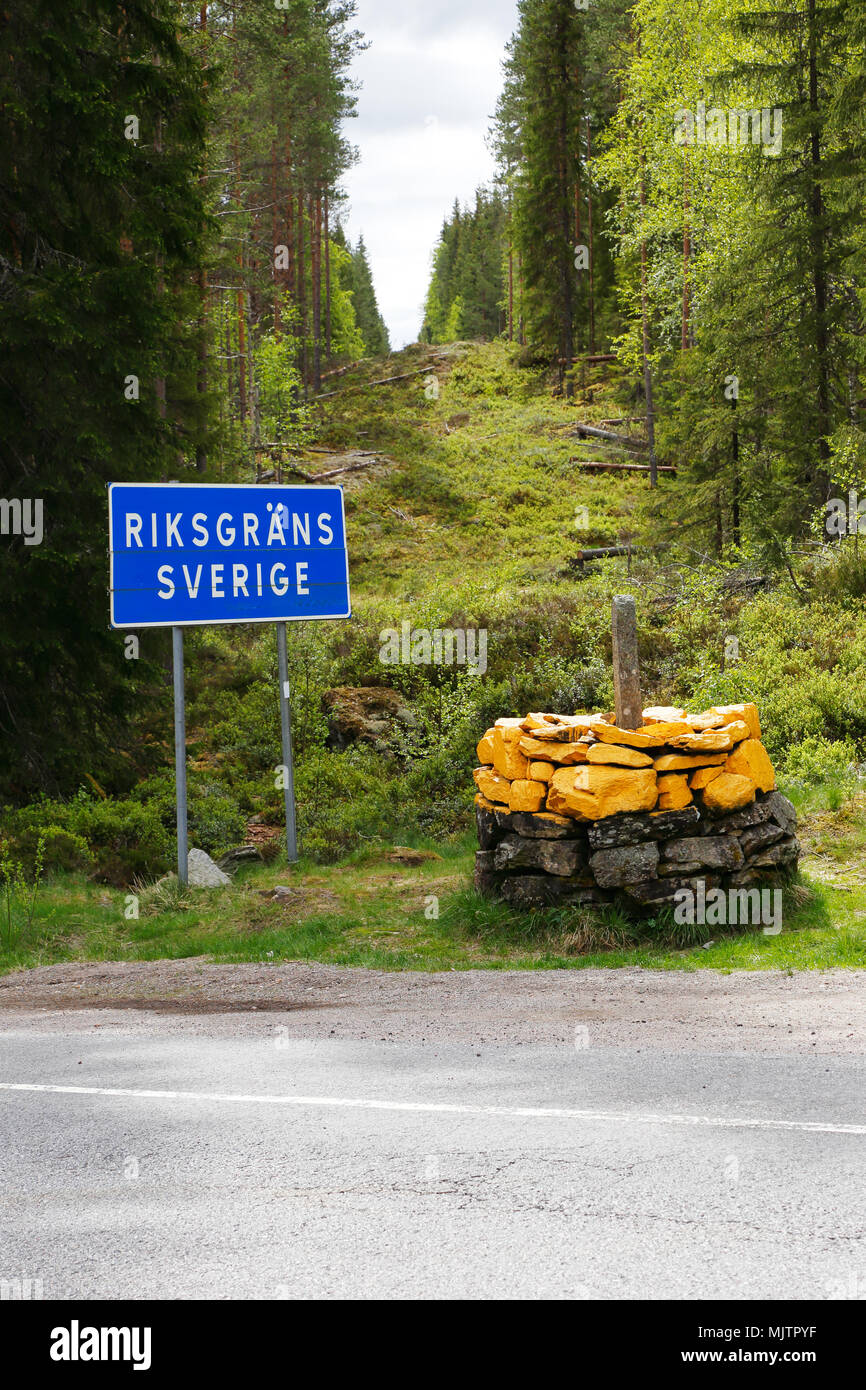 International boundary between Norway and Sweden with the landmark and a cut border line in the forest between the two countries with Sweden on the le Stock Photo