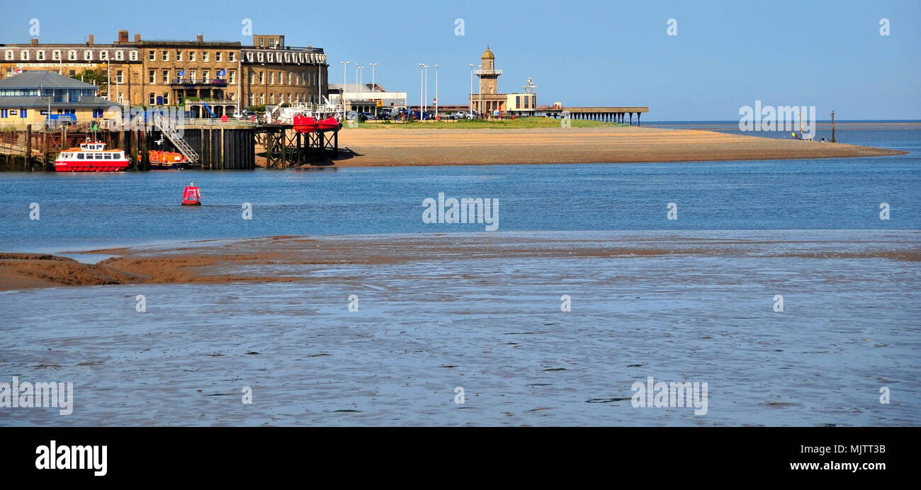 Blue sky view from Knott End across the River Wyre to the North Euston Hotel building, Lower Lighthouse and Fleetwood Pier, Fleetwood, Lancashire, UK Stock Photo