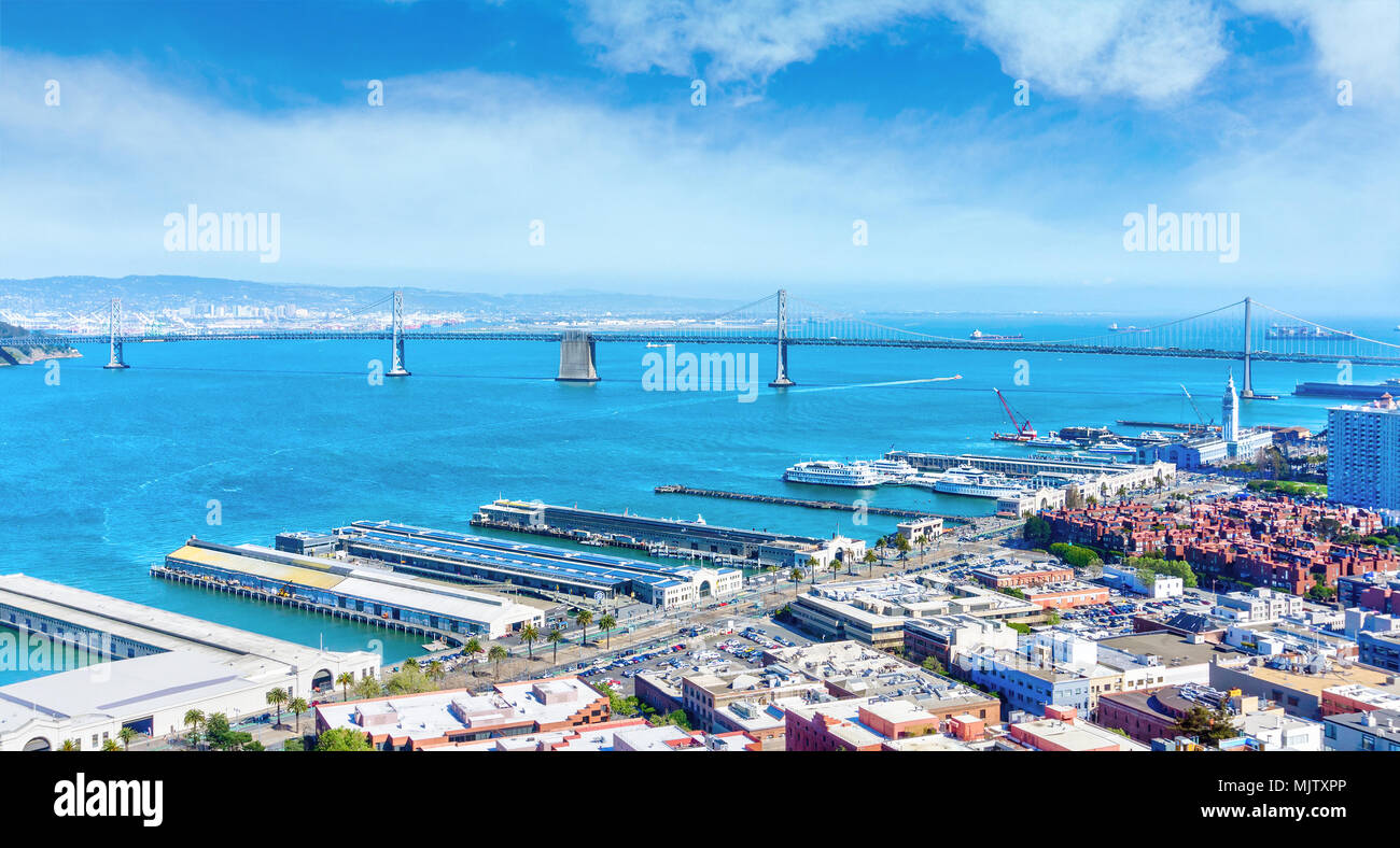 Panorama of the Embarcadero waterfront showing the Port of San Francisco and the double-decked Bay Bridge across the San Francisco Bay. Aerial view. Stock Photo