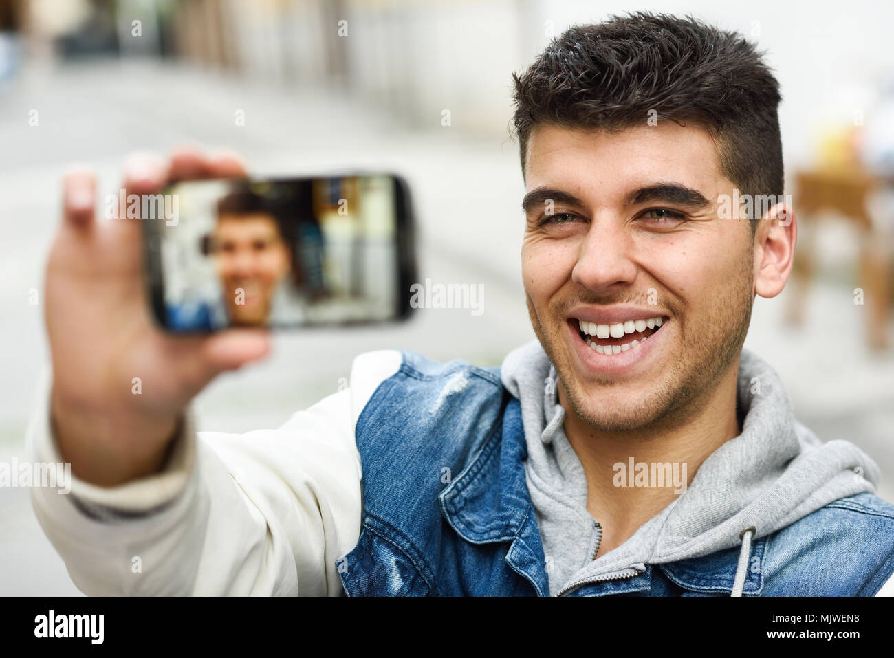 Handsome young man selfie in urban background with a smartphone wearing casual clothes Stock Photo