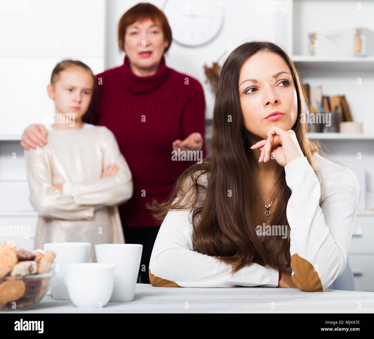 Chagrined young woman having conflict with little daughter and mother ...