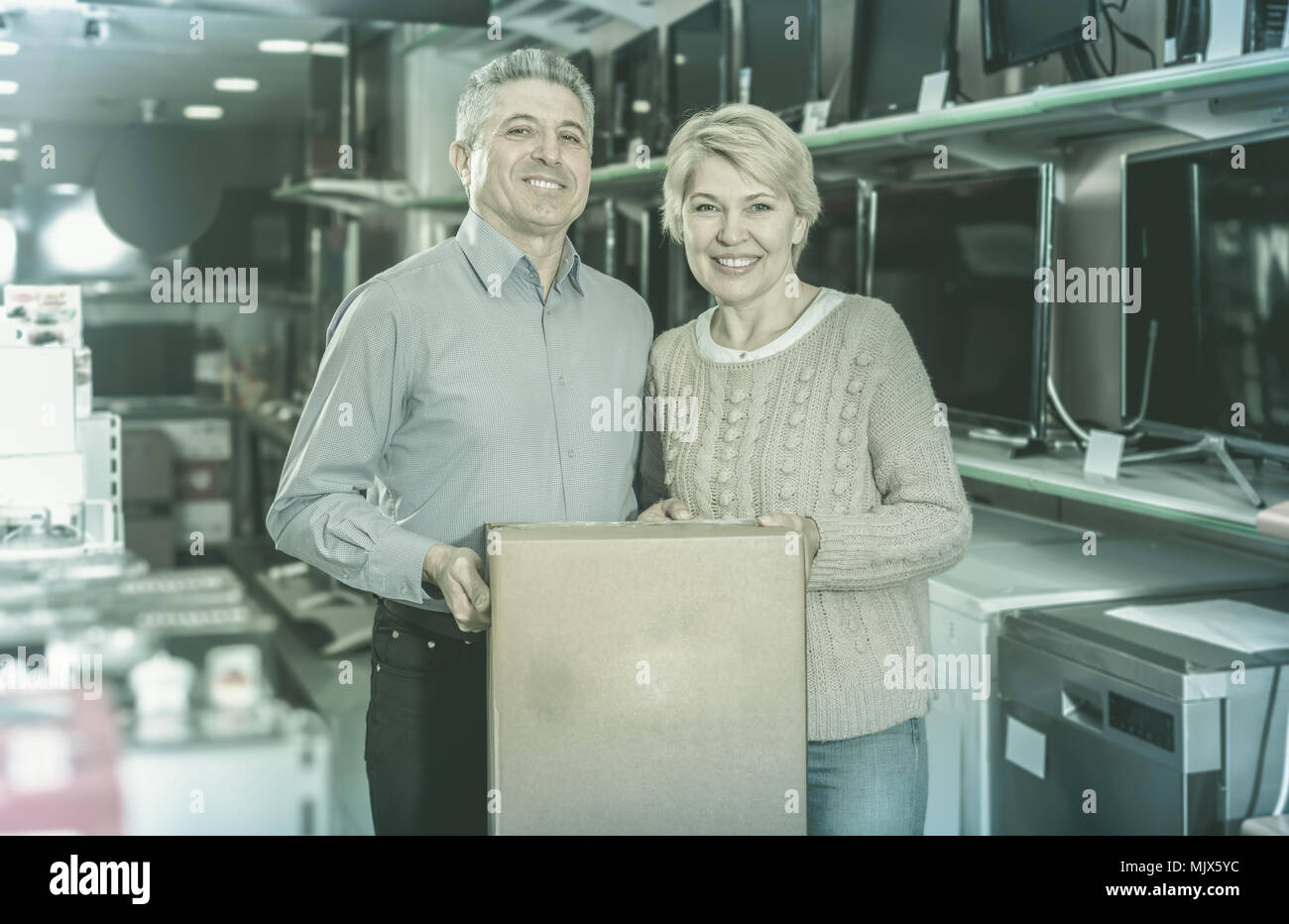 smiling mature married couple in shop packed household appliances into boxes for transportation to themselves home Stock Photo