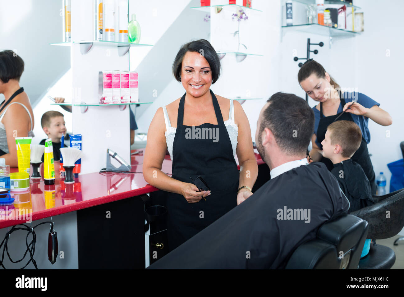 smiling woman hairdresser asking man how to cut his hair in crowded