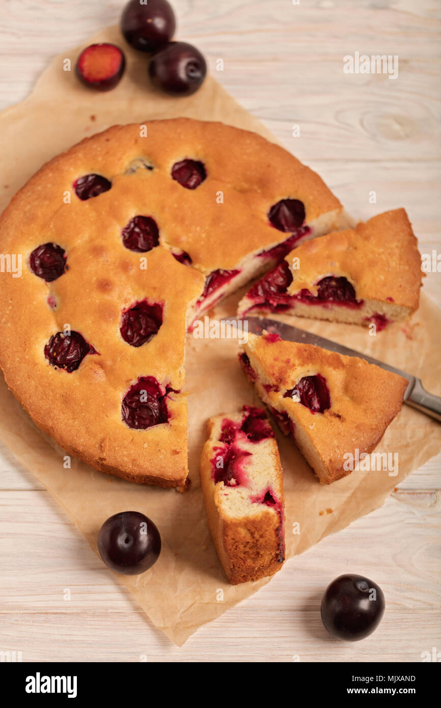 Home plum pie on baking paper. Selective focus. Stock Photo