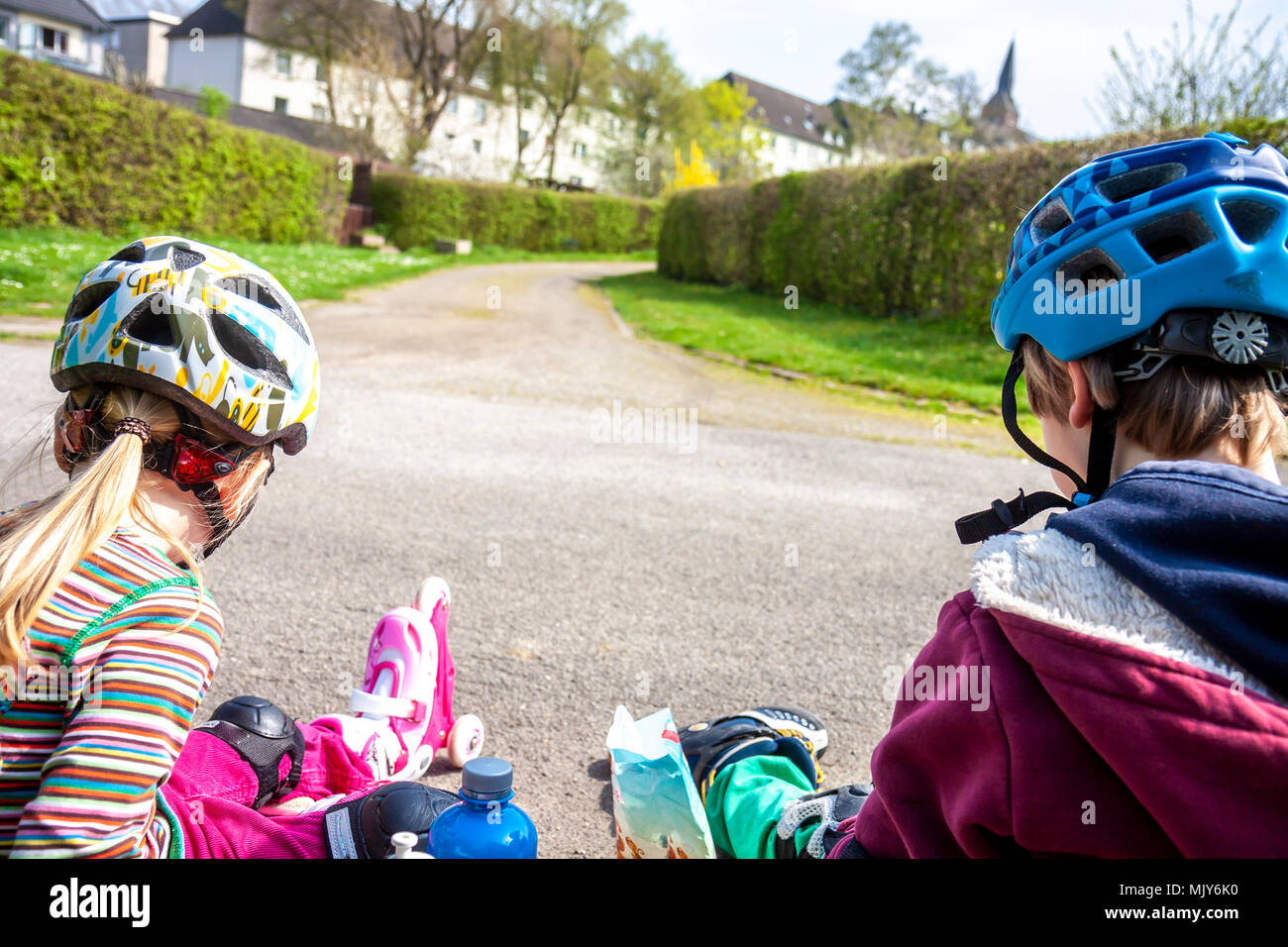 Boy and girl wearing rollerblades sitting and eating and drinking