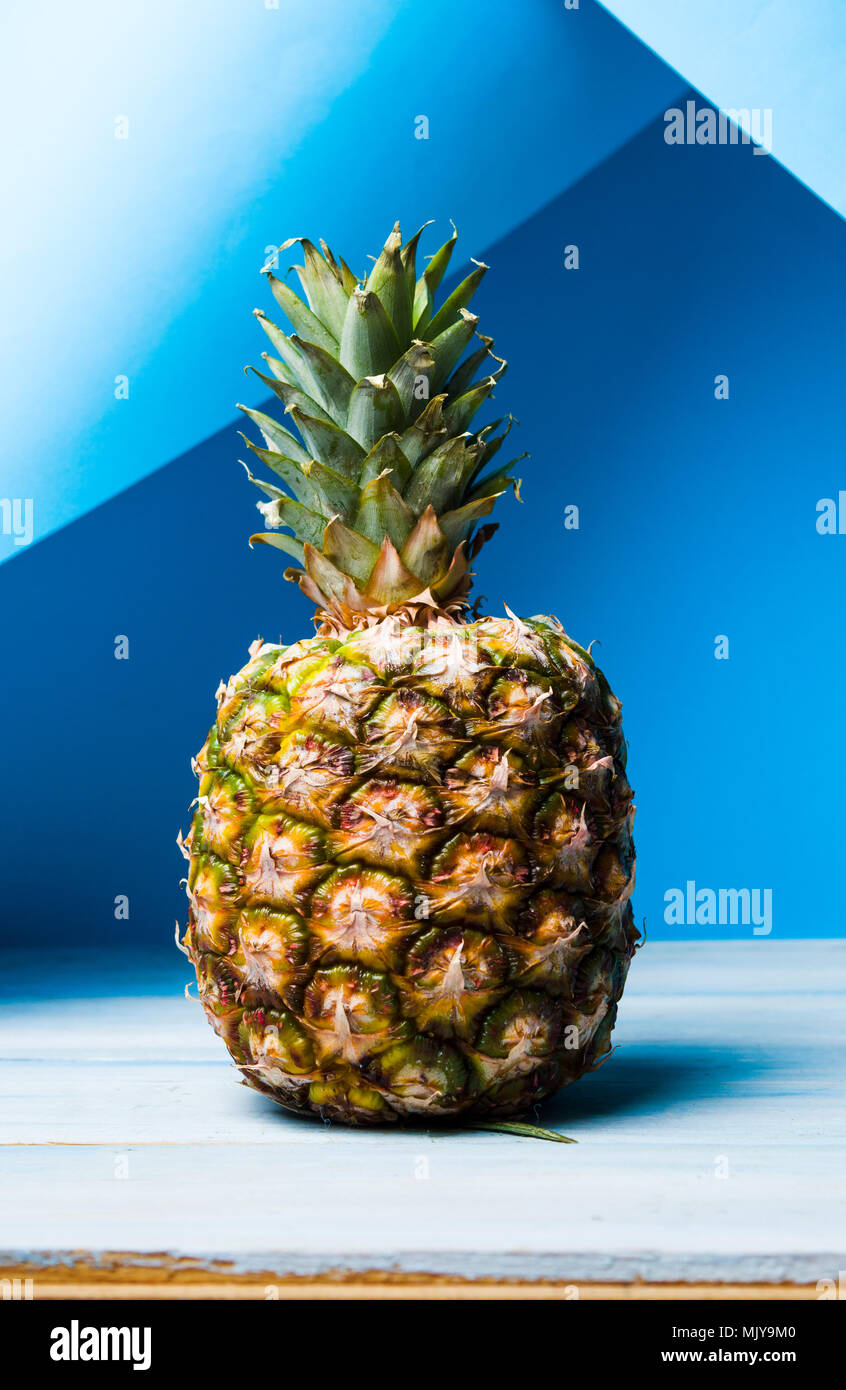 Whole pineapple fruit against blue background Stock Photo