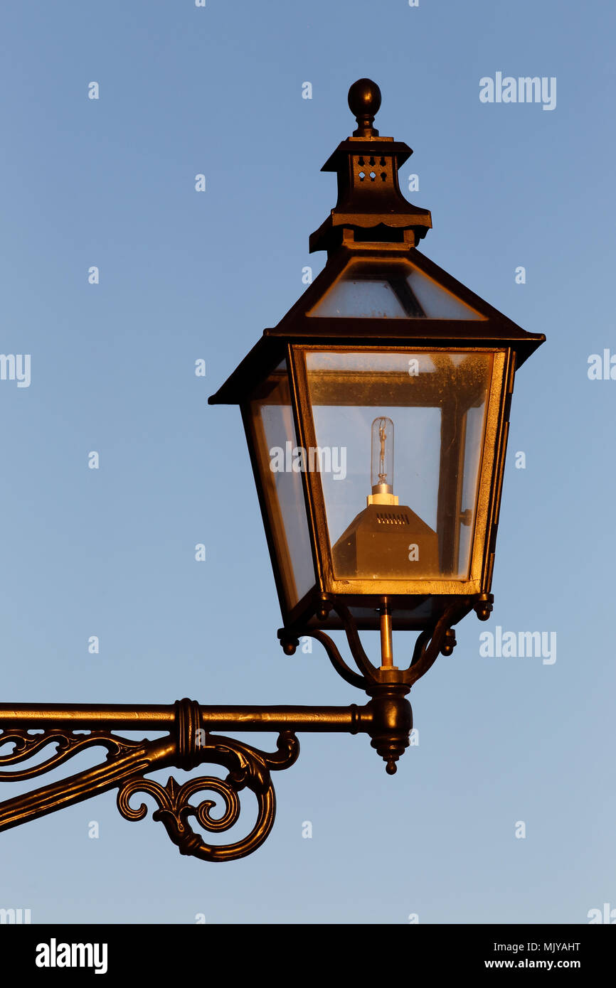 Close-up of an old style street lamp with a modern light bulb inside. Stock Photo