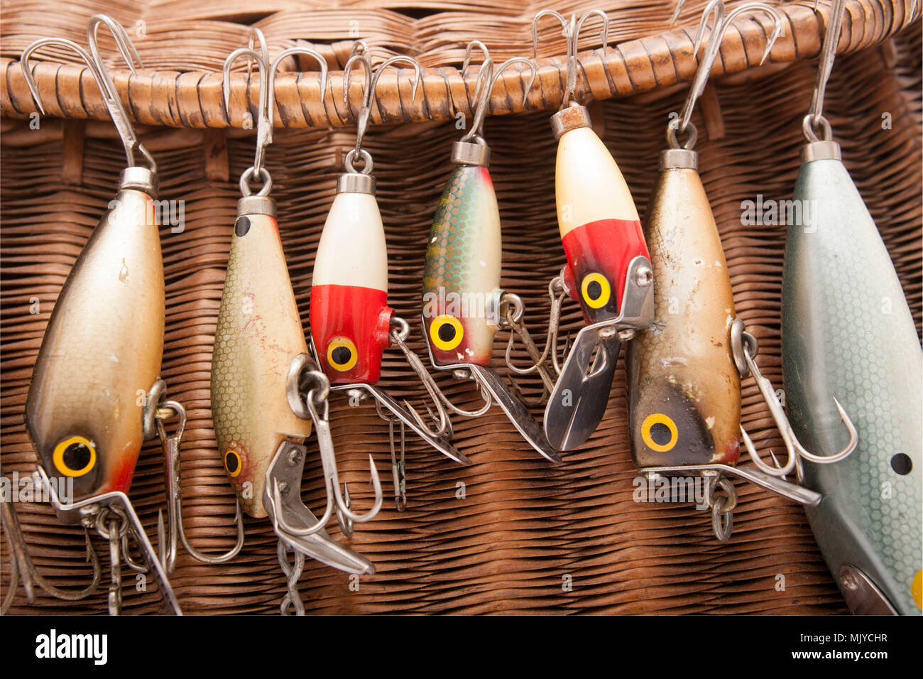 A selection of vintage fishing lures, also known as plugs, possibly made by Woods MFG. They are shown displayed on a woven fishing creel. Dorset Engla Stock Photo