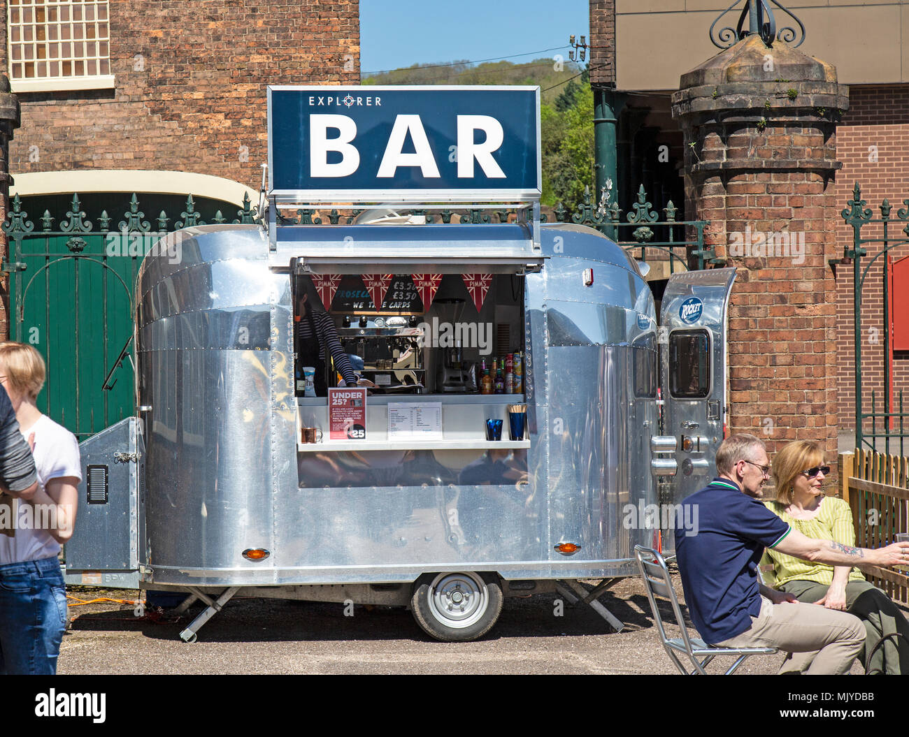 A mobile bar in the shape of a metal trailer, selling alcoholic drinks