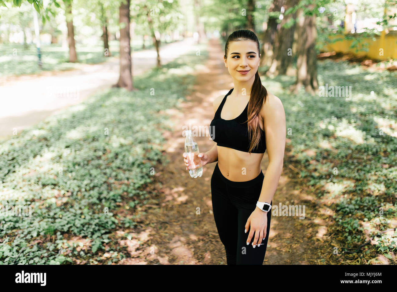 Young woman resting after jogging in park, she is drinking water Stock ...