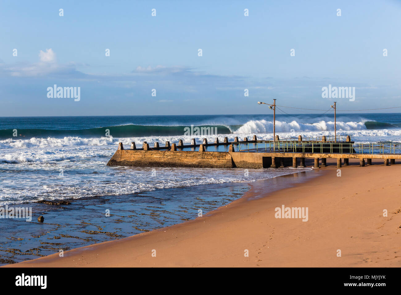 Ocean waves breaking crashing front of tidal swimming pool beach