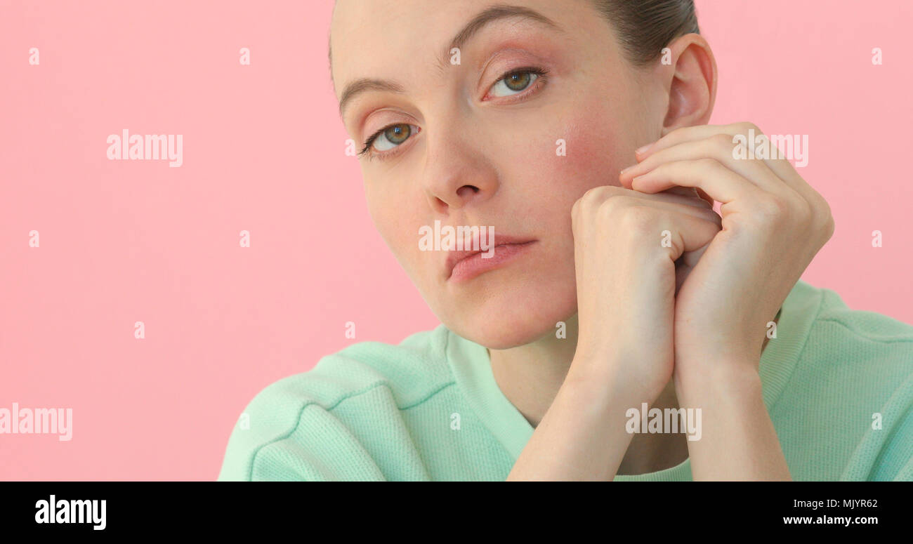 Young bored woman closeup at pink background Stock Photo
