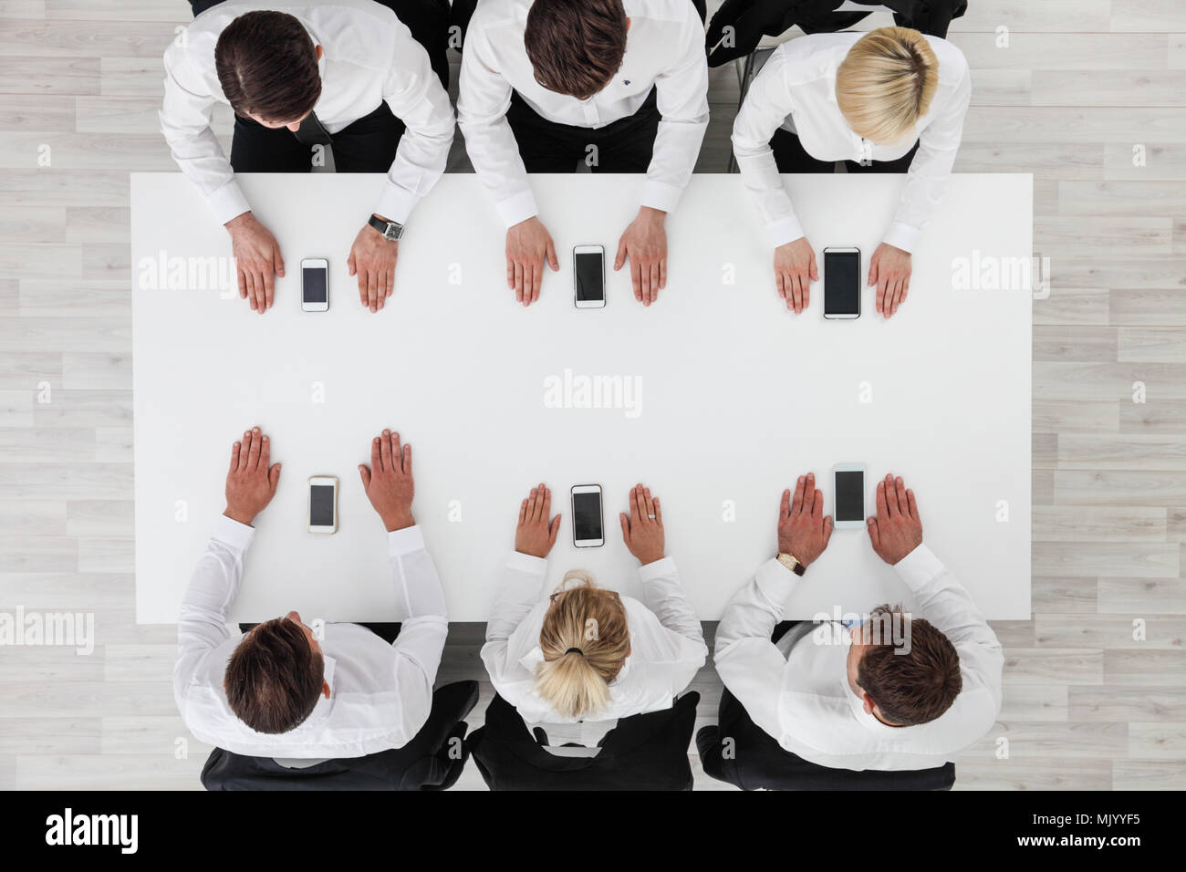 Business people not using smartphones sitting around white table Stock Photo