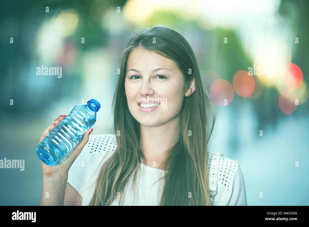 Attractive girl drinking water during walk around city in hot summer