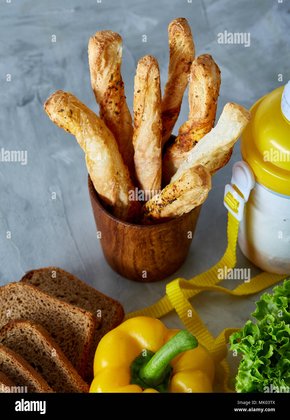 Continental breakfast with fresh pastry, vegetables, greenery and beverages over light textured background, top view. Yummy homemade bread, bell peppe Stock Photo