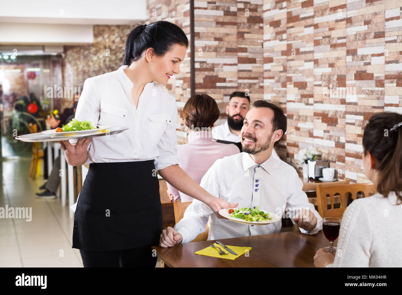 Positive waitress taking table order and smiling at the tavern Stock Photo  - Alamy
