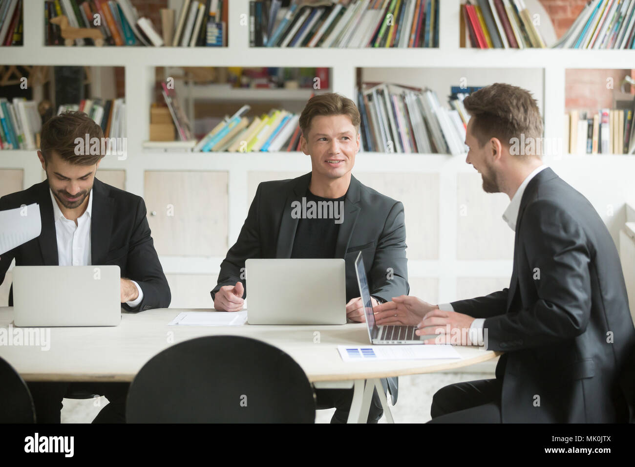 Three male colleagues brainstorming and discussing ideas Stock Photo
