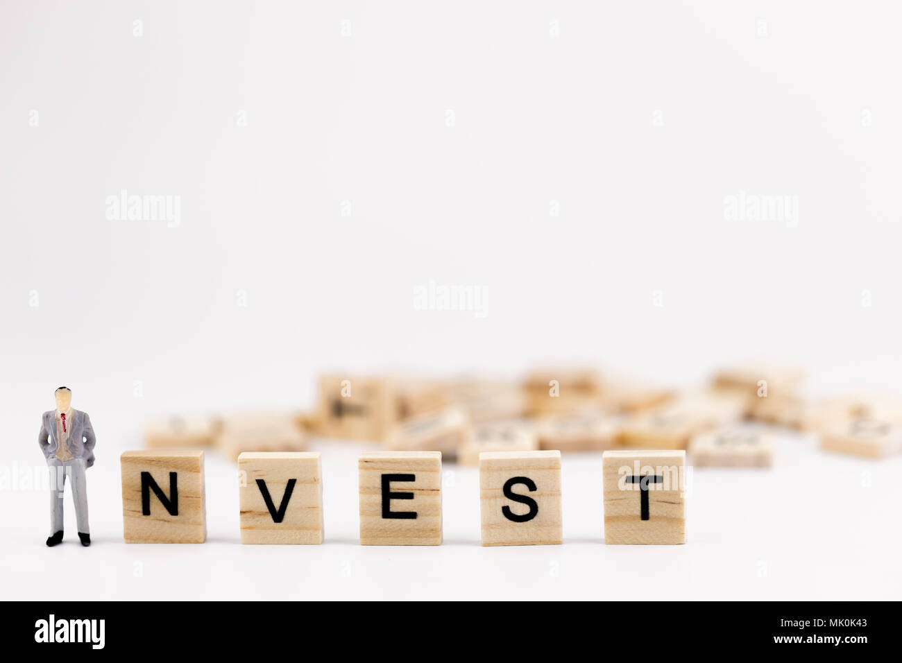Business investment concept. Miniature people small figure businessman standing first in a wooden cube with word invest on white background. With copy Stock Photo