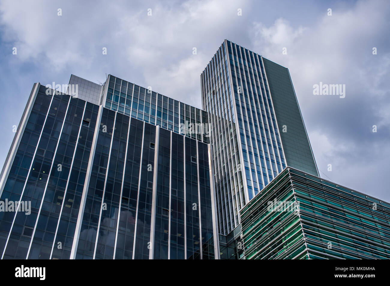 Tightly standing modern glass office buildings against cloudy sky. Stock Photo
