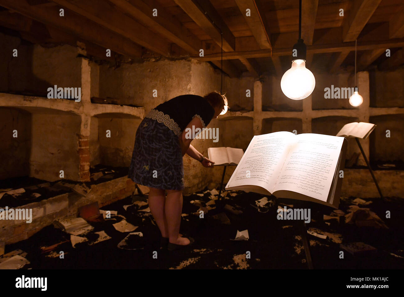 A visitor views books in the cellar of Blickling Hall in Norfolk which has been recreated to depict a university library destroyed by militants in Mosul, Iraq as part of the new art installation 'The Word Defiant!' which reveals stories of books that have been banned, burned, redacted, drowned, neglected and superseded. Stock Photo