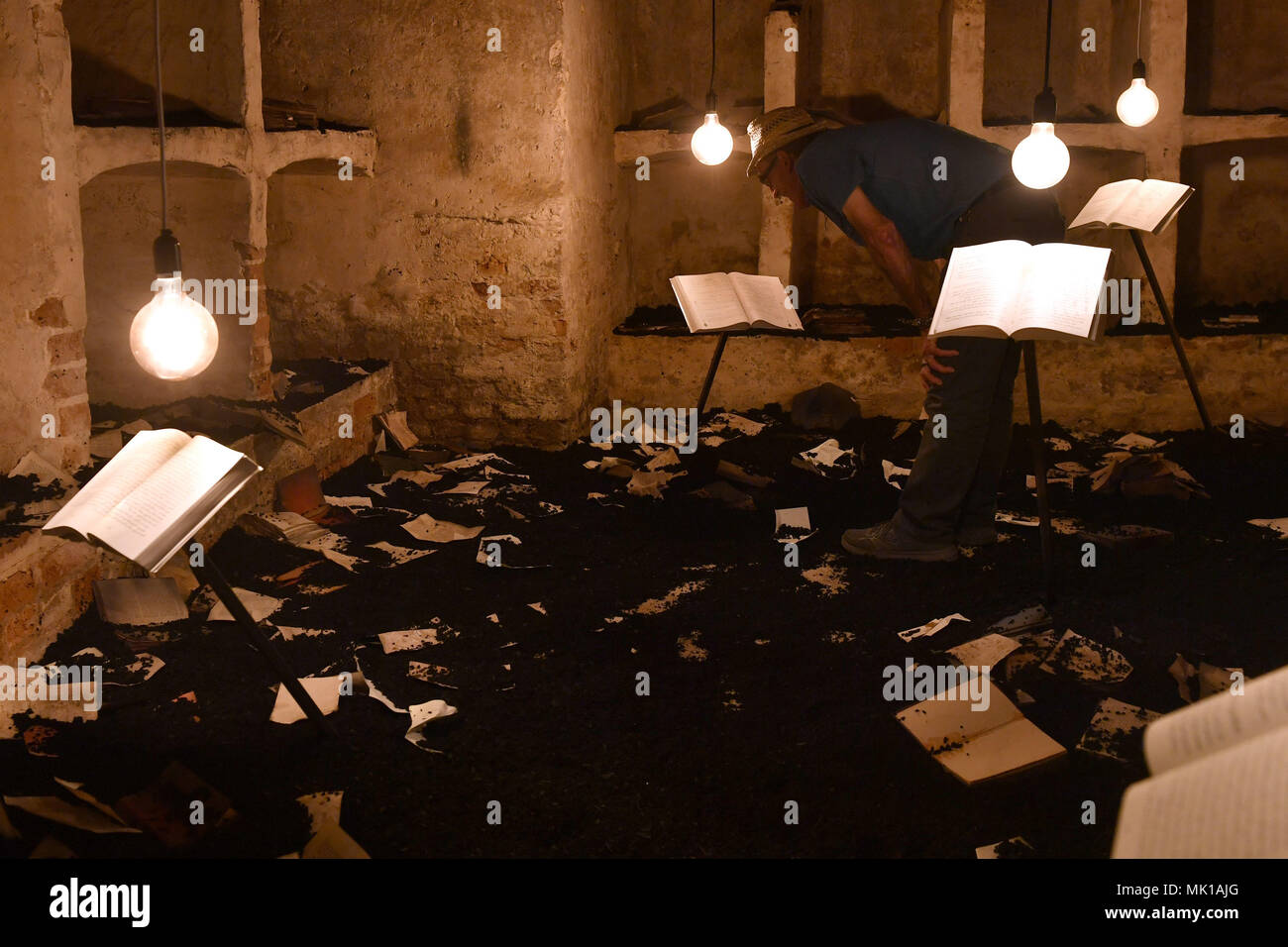A visitor views books in the cellar of Blickling Hall in Norfolk which has been recreated to depict a university library destroyed by militants in Mosul, Iraq as part of the new art installation 'The Word Defiant!' which reveals stories of books that have been banned, burned, redacted, drowned, neglected and superseded. Stock Photo