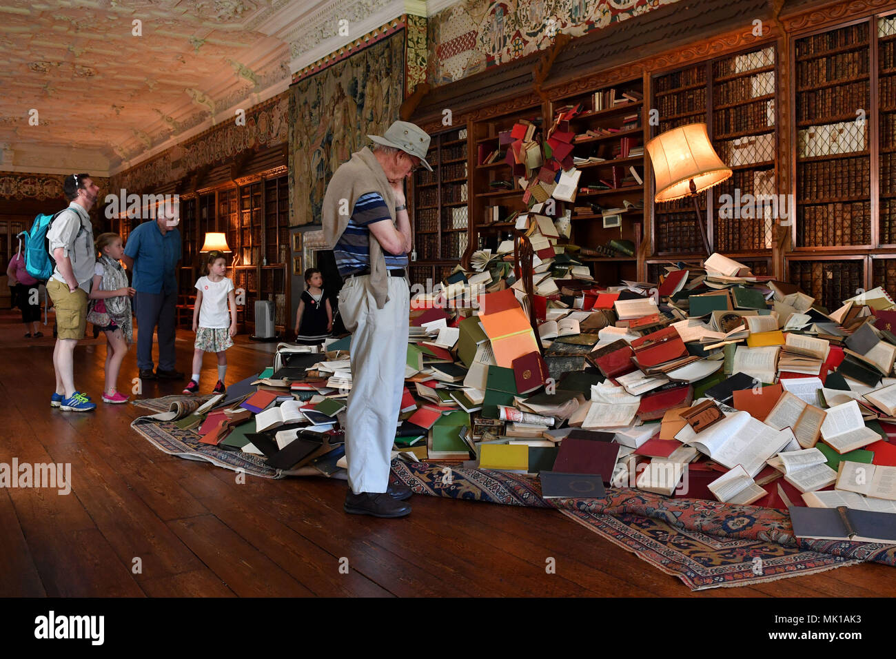 Visitors view a cascade of books flowing from bookcases at Blickling Hall in Norfolk as part of the new art installation 'The Word Defiant!' which reveals stories of books that have been banned, burned, redacted, drowned, neglected and superseded. Stock Photo