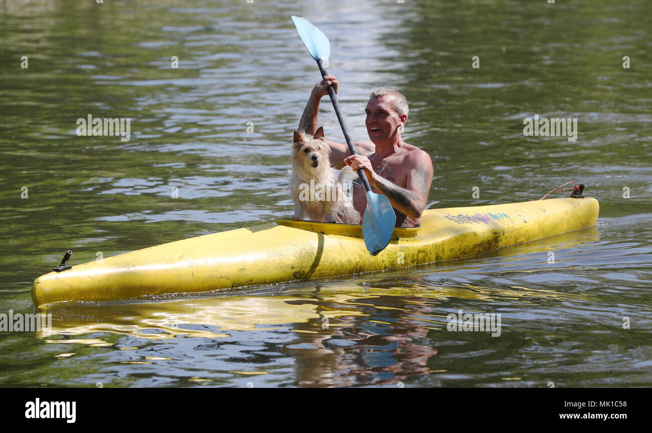 Veron Pimm, accompanied by his canine passenger Bibi, kayaks along the River Thames close to Boulter's Lock in Maidenhead Riverside, Berkshire. Sun worshippers are set to sizzle in the spring heatwave, with Bank Holiday Monday forecast to be the hottest since records began. Stock Photo