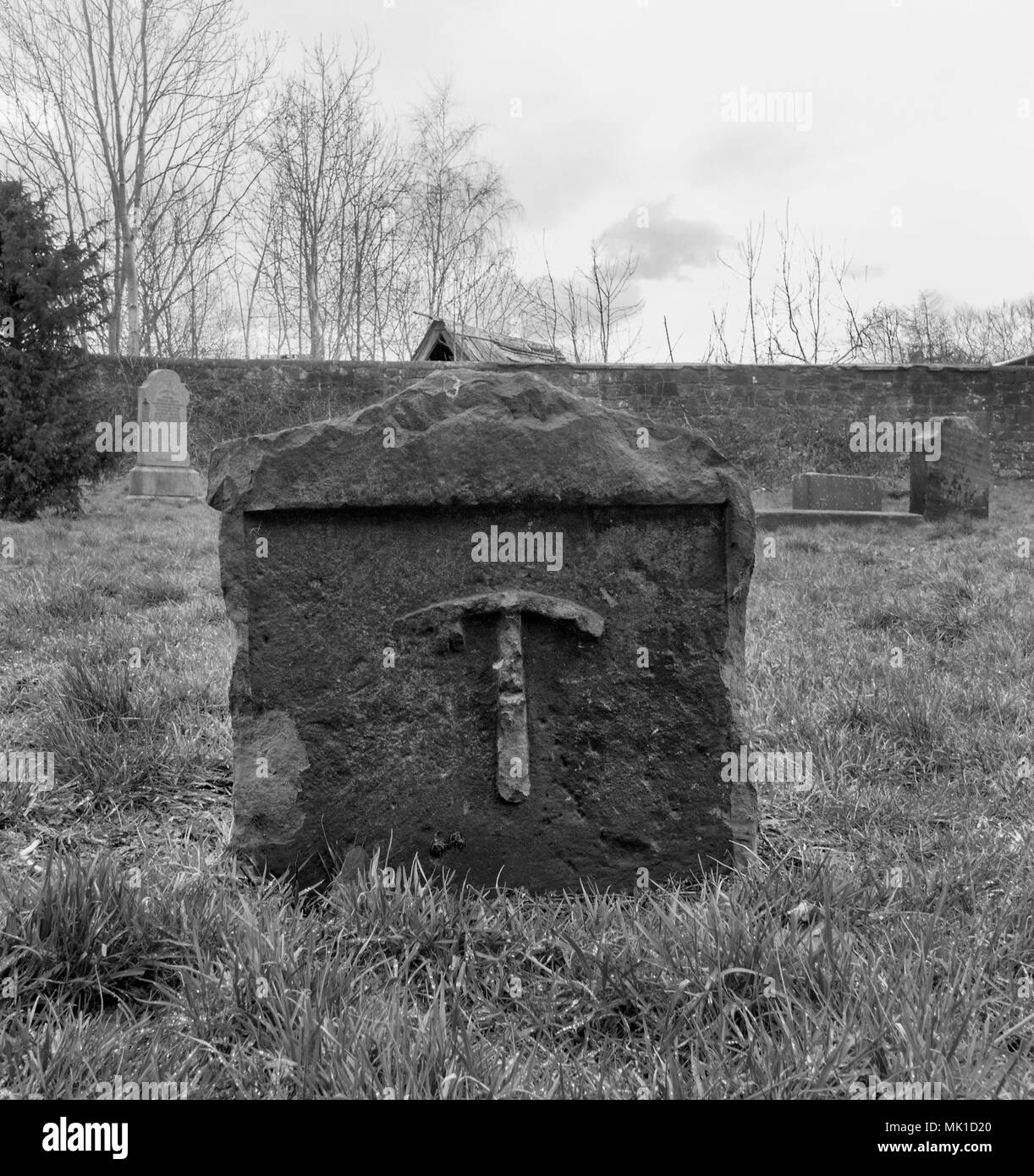 GLASGOW, SCOTLAND - MARCH 27th 2018: A black and white photograph of a pickaxe on a gravestone at the Govan Old Parish Church. Stock Photo