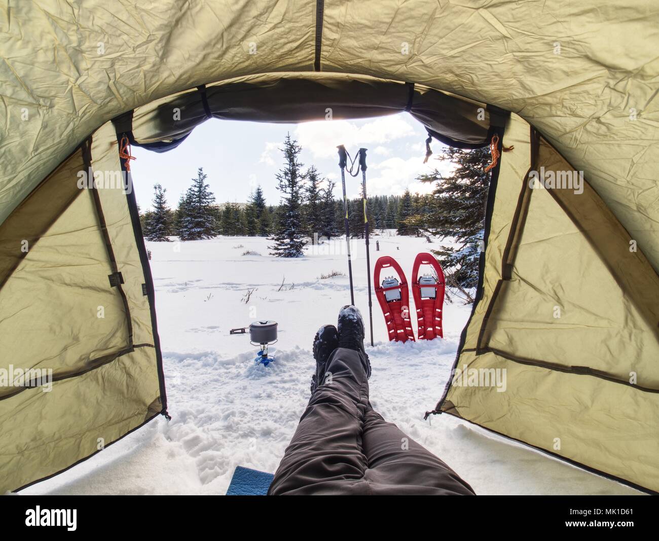 Cooking in front of tent in snow. Hiker camping in winter mountains