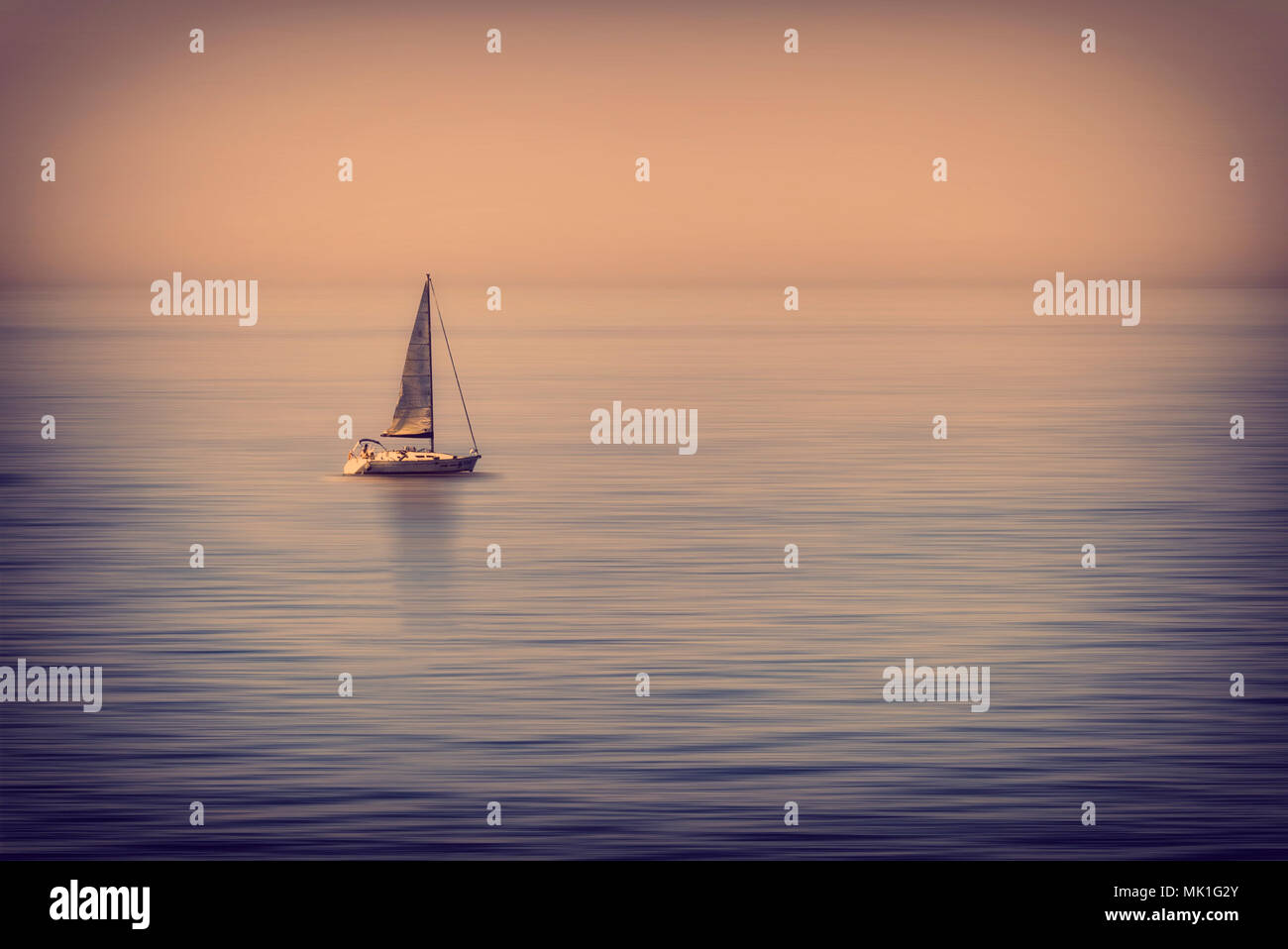 lonely sailboat in the middle of the calm sea at sunset Stock Photo - Alamy