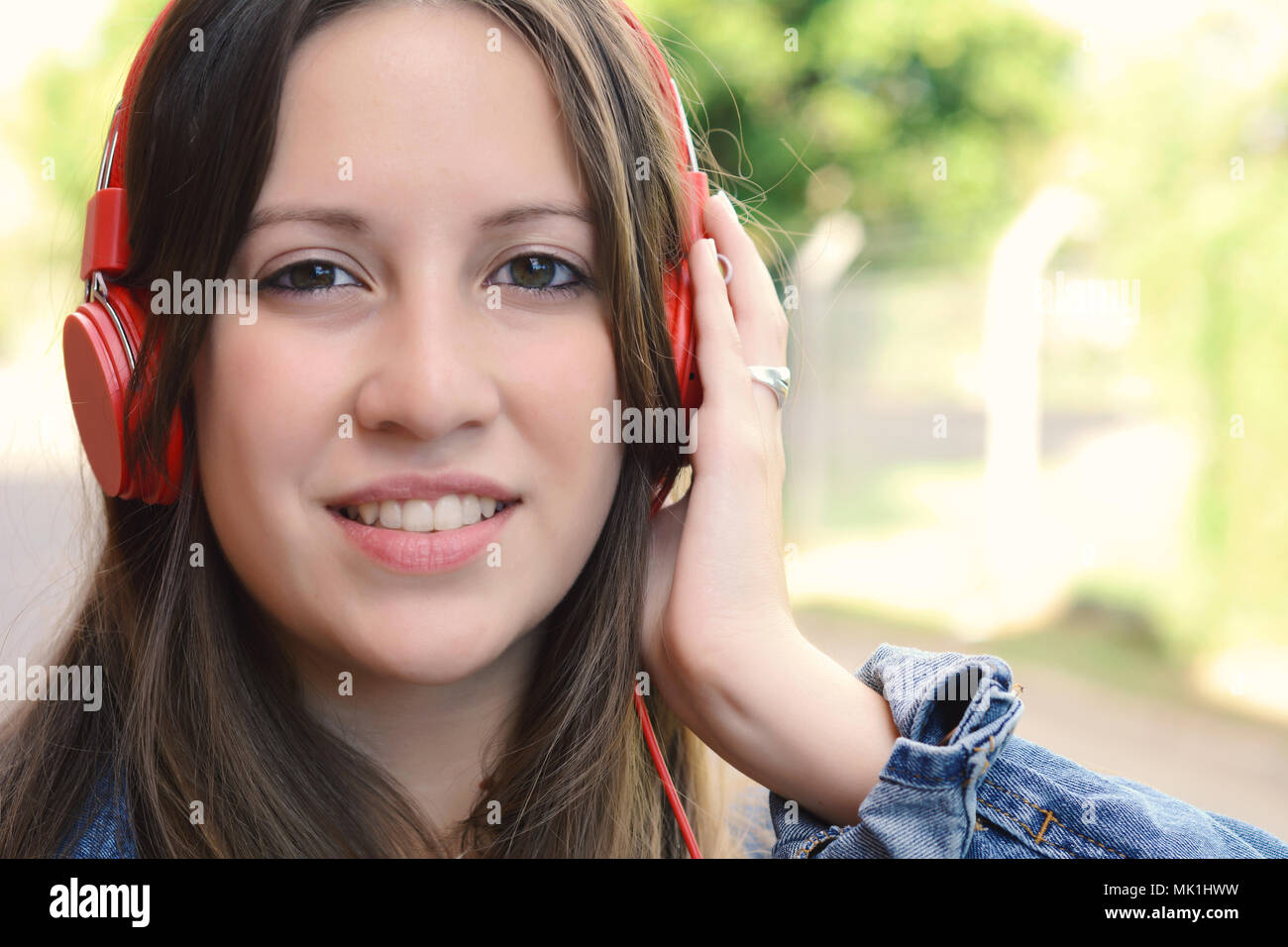 Portrait of young beautiful woman listening to music with red ...