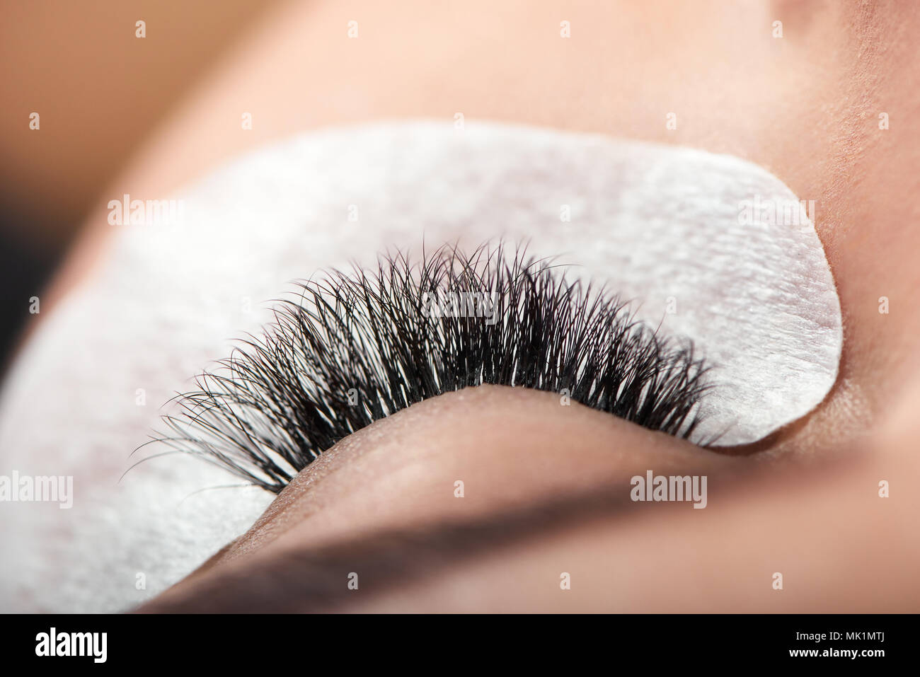 Close up of long enlarged woman's lashes. beatifully and accurately made by professional in modern beaty salon. Healthy, young skin with cosmetic stickers for lashes enlarging. Stock Photo