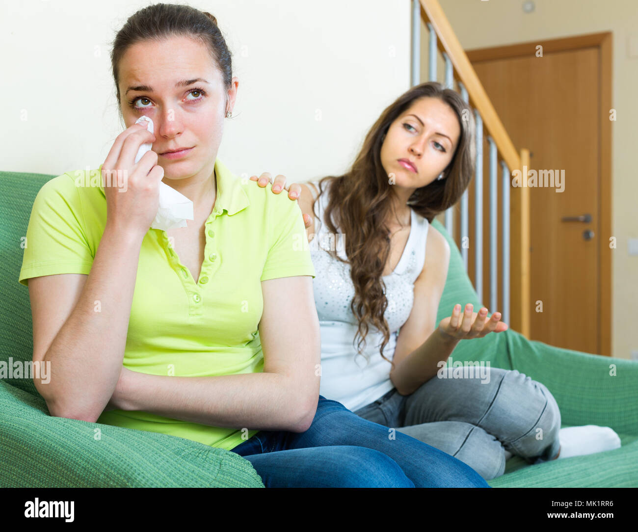 Two offended young women sitting on sofa after quarrel at home Stock Photo