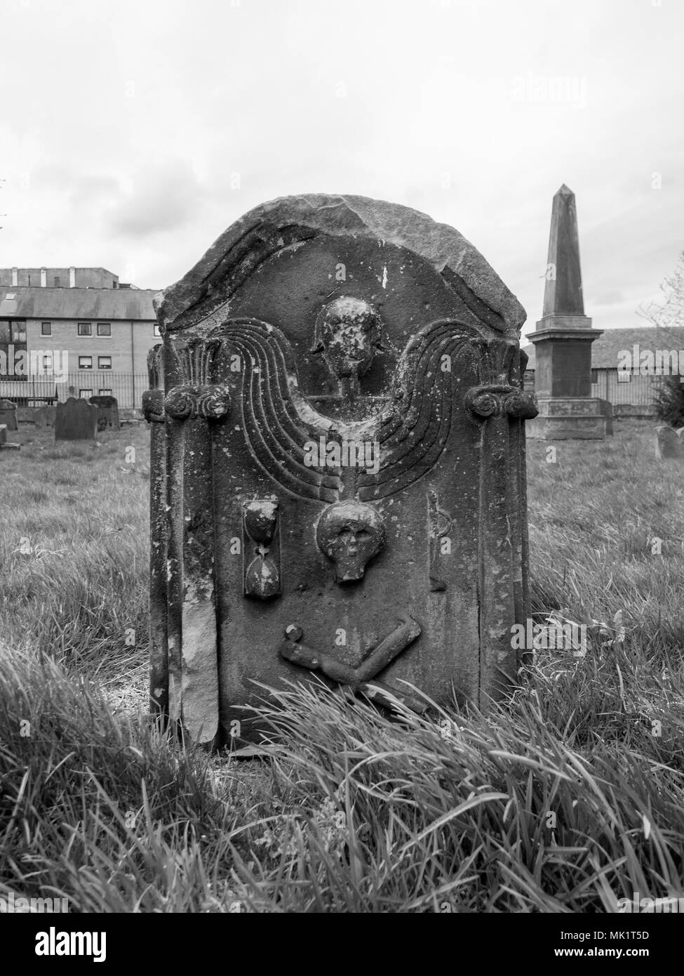 GLASGOW, SCOTLAND - APRIL 23rd 2018: A black and white photograph of an angel, a skull and bone cross on a gravestone at the Govan Old Parish Church. Stock Photo